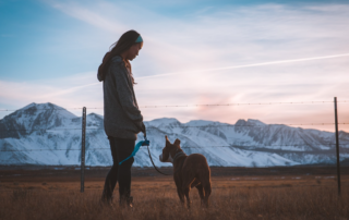 woman with dog in front of snow-capped mountains